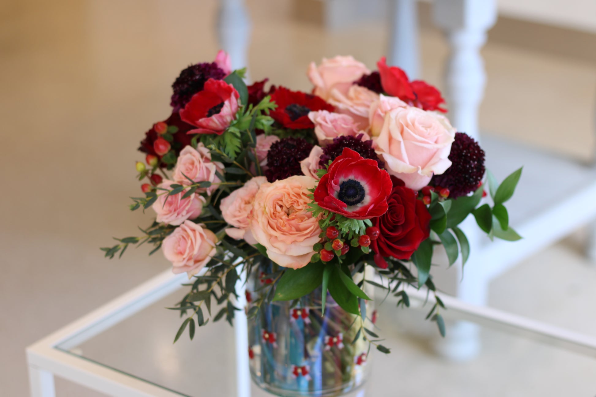 peach and red roses with red anemones in clear vase